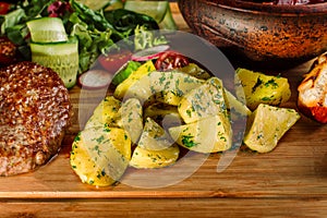 Potato country style with dill in clay bowl on wooden background