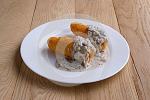 Potato cutlet in breading stuffed with ham served with mushroom sauce