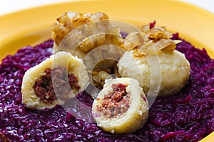 potato dumplings filled with smoked meat with fried onion on red cabbage