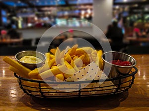 Potato french fries served in a metalic basket with two different sauces