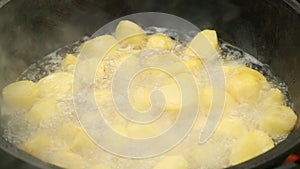 Potato is frying in cauldron in boiling hot oil on nature on fire, closeup view.