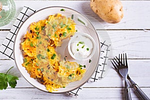 Potato latkes with herbs and sour cream on a plate on the table top view
