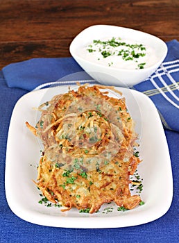 Potato Latkes and sour cream, vertical.