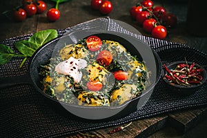 Potato pan with spinach, vegetarian cuisine, on dark rustic table