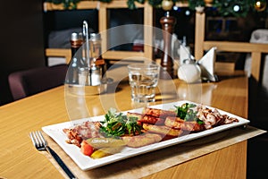 Potato pancakes with bacon on a white rectangular plate on a table in a restaurant. Table setting at the restaurant