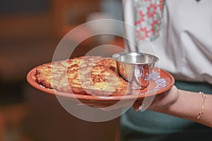 Potato pancakes dranik with sour cream, traditional Ukrainian dish. Waiter in traditional uniform serving dranyki.