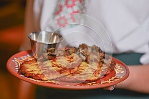 Potato pancakes dranik with sour cream, traditional Ukrainian dish. Waiter in traditional uniform serving dranyki.