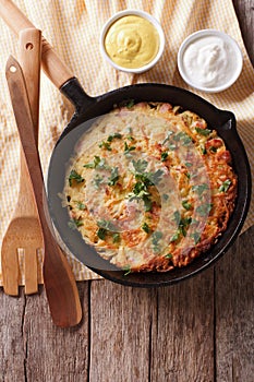 Potato pancakes with herbs in a frying pan. vertical top view