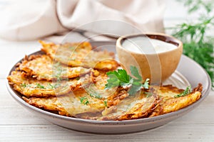 Potato pancakes or latkes or draniki with sour cream in plate on white wooden table