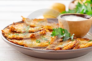 Potato pancakes or latkes or draniki with sour cream in plate on white wooden table