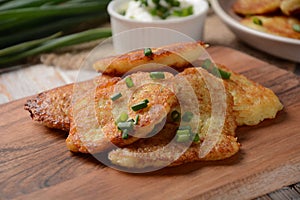 Potato pancakes or latkes or draniki with sour cream in plate on wooden table