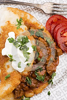 Potato pancakes with meat, vegetable, tomato and parsley