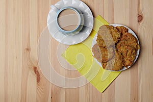 potato pancakes in a plate and a cup of coffee on a wooden background
