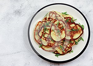 Potato pancakes on a round plate on a light gray background