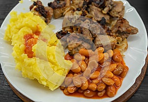 Potato puree with white beans, meat and onion on a white plate close-up