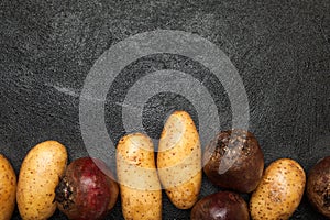 Potato and red beets tubers on a black table. Copy space