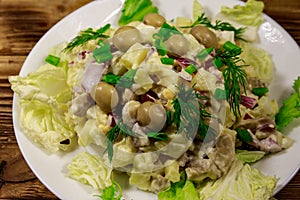 Potato salad with marinated mushrooms, eggs, red onion and mayonnaise on wooden table