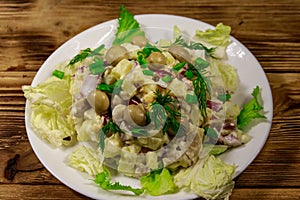 Potato salad with marinated mushrooms, eggs, red onion and mayonnaise on a wooden table