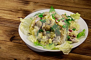 Potato salad with marinated mushrooms, eggs, red onion and mayonnaise on wooden table