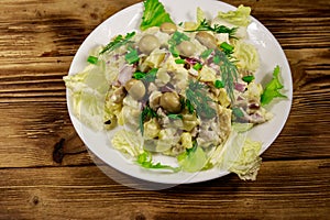 Potato salad with marinated mushrooms, eggs, red onion and mayonnaise on wooden table