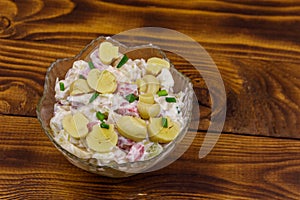 Potato salad with marinated mushrooms, sausage, onion and mayonnaise on wooden table