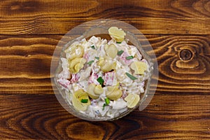 Potato salad with marinated mushrooms, sausage, onion and mayonnaise on wooden table