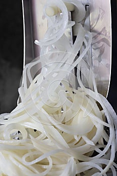 Potato on a spiralizer being cut into thin strips.