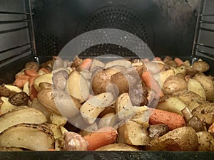 Potato with vegetables baked in the oven, close-up. The process of cooking potatoes in an electric grill. Baked potatoes with