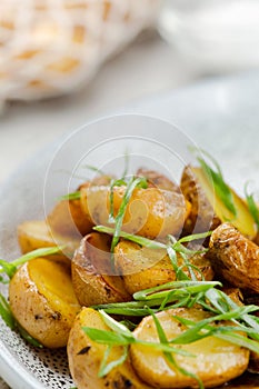 Potato wedges, oven roasted close up on light concrete background. Roasted baby potatoes. fries potatoes with green onions