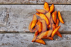 Potato wedges on wooden backdrop.