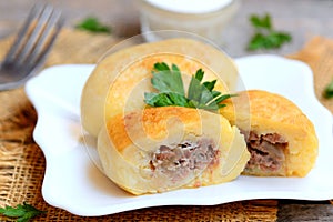Potato zrazy with a meat filling on a white plate and a vintage wooden table. Traditional Ukrainian zrazy recipe. Closeup