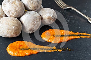 Potatoes on a black plate with red sauce. A traditional Canarian dish is papas arrugadas. photo