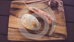 Potatoes and carrots crop on a wooden garden table background