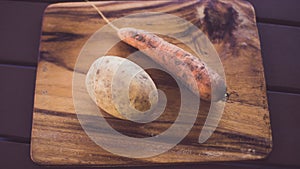 Potatoes and carrots crop on a wooden garden table background