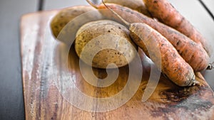 Potatoes and carrots crop on a wooden garden table background