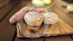 Potatoes and carrots crop on a wooden garden table background