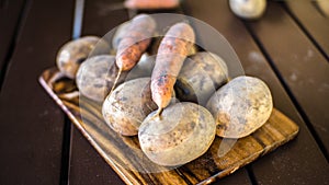 Potatoes and carrots crop on a wooden garden table background