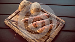 Potatoes and carrots crop on a wooden garden table background
