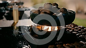 Potatoes are cooked in a frying pan on the fire in the outdoor kitchen.