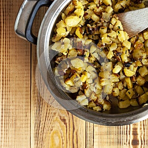 Potatoes fried with garlic and herbs, served in a apen, wooden background