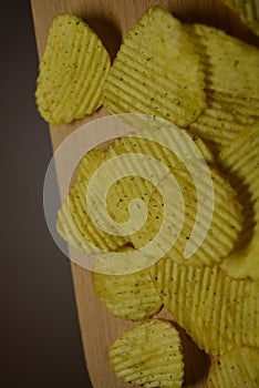 Potatoes fried wavy, embossed, potato chips with sour cream and greens, facies on a wooden board