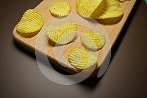 Potatoes fried wavy, embossed, potato chips with sour cream and greens, facies on a wooden board