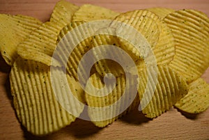 Potatoes fried wavy, embossed, potato chips with sour cream and greens, facies on a wooden board