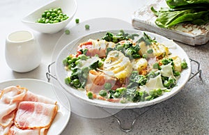 Potatoes gnocchi, green peas, shinach abd bacon  on white  plate close up photo