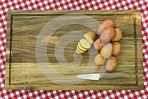 Potatoes and knife on wooden plate