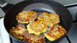 Potatoes pancakes, draniki cooking in frying pan on gas oven on kitchen.