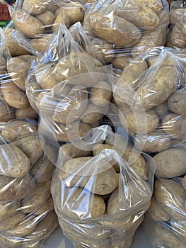 Potatoes in plastic bags stocked for sale.