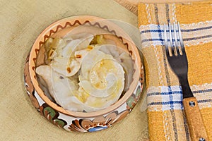 Potatoes varenyky topped with fried onion in bowl, top view