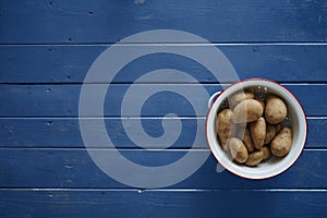 Potatoes in a white sieve on blue table