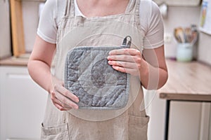 A potholder in the hands of a woman in the kitchen. Female hands holding a kitchen towel